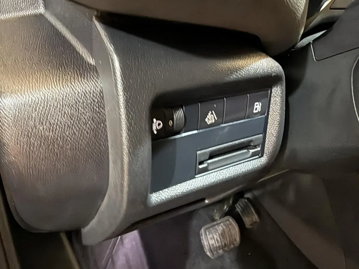 Gros plan sur les commandes latérales noires du tableau de bord du Citroën C5 Aircross bleu, avec pédales visibles en dessous.