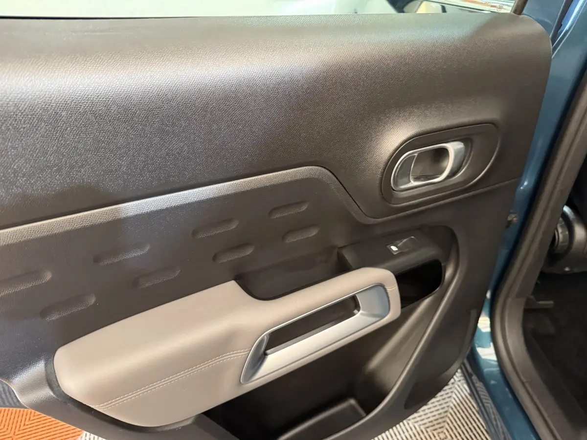 Gros plan sur la porte avant gauche bleu du Citroën C5 Aircross Hybrid avec accoudoir beige et poignée argentée.