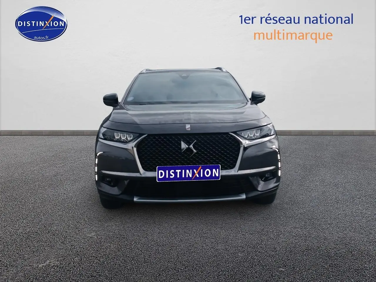 Vue frontale d'un DS7 Crossback E-tense gris platinium avec calandre noire et feux LED distinctifs allumés.