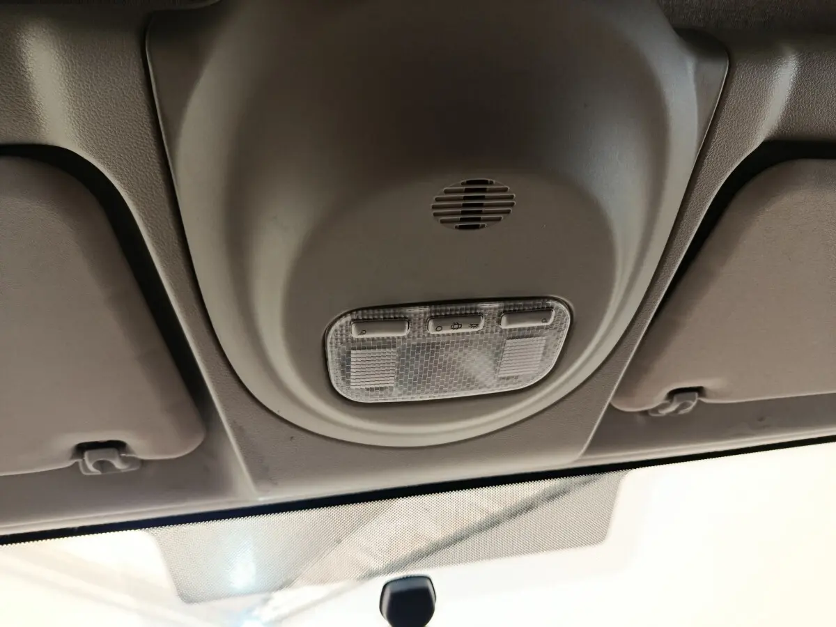 Plafonnier intérieur beige avec commandes d’éclairage, vue en contre-plongée depuis l’avant du Peugeot Partner blanc.