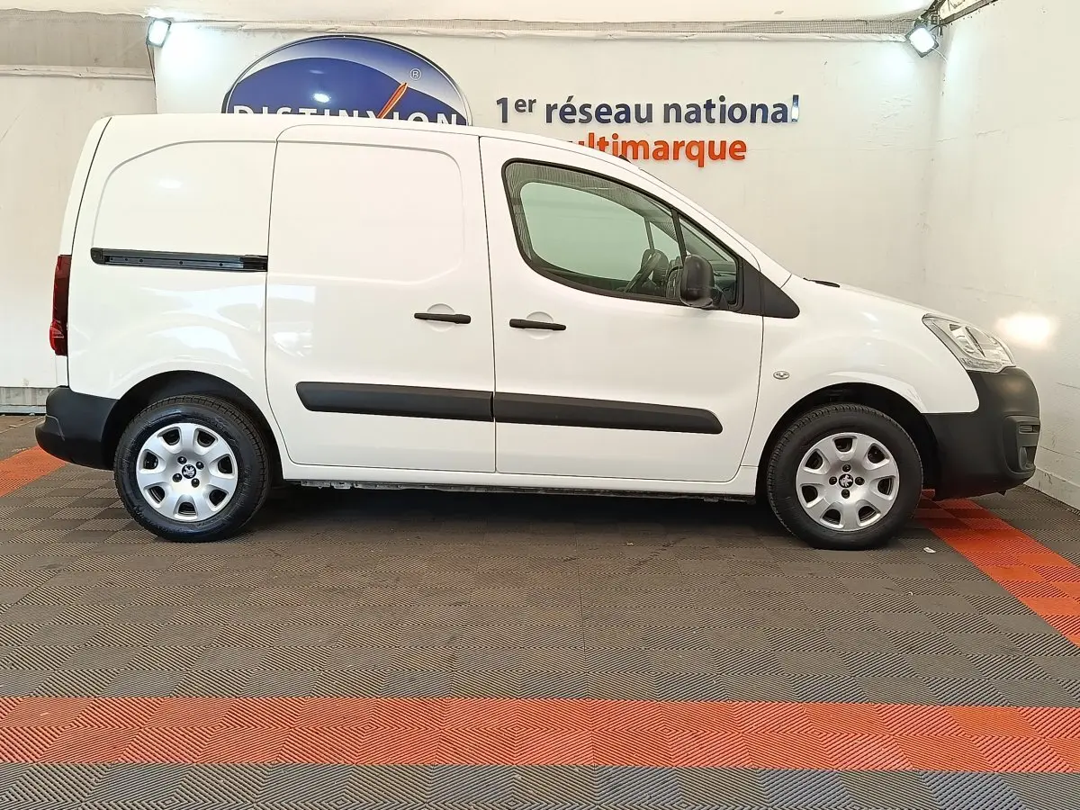 Vue latérale droite d'un utilitaire Peugeot Partner blanc 2018 avec protections noires et jantes acier.