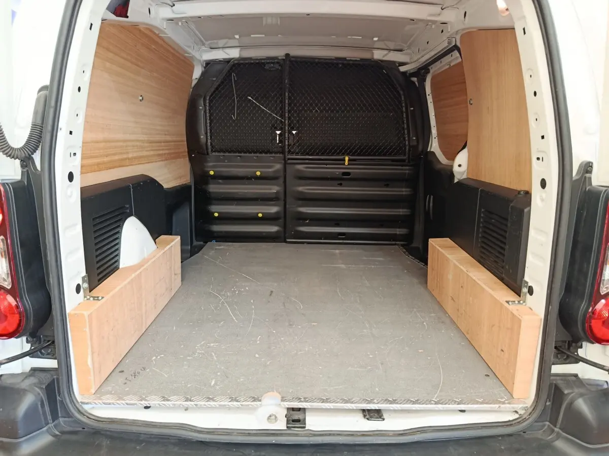 Vue arrière du coffre blanc du Peugeot Partner 1.6 BlueHDi 100 Long Pro avec cloison tubulaire et aménagement bois.