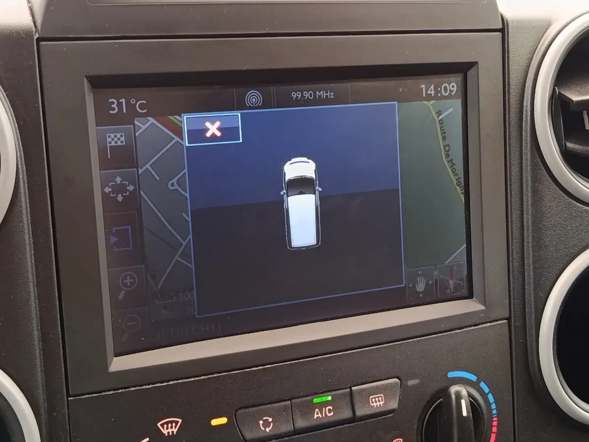Écran de navigation intérieur montrant une vue en plan du Peugeot Partner blanc, tableau de bord et commandes climatisation visibles.