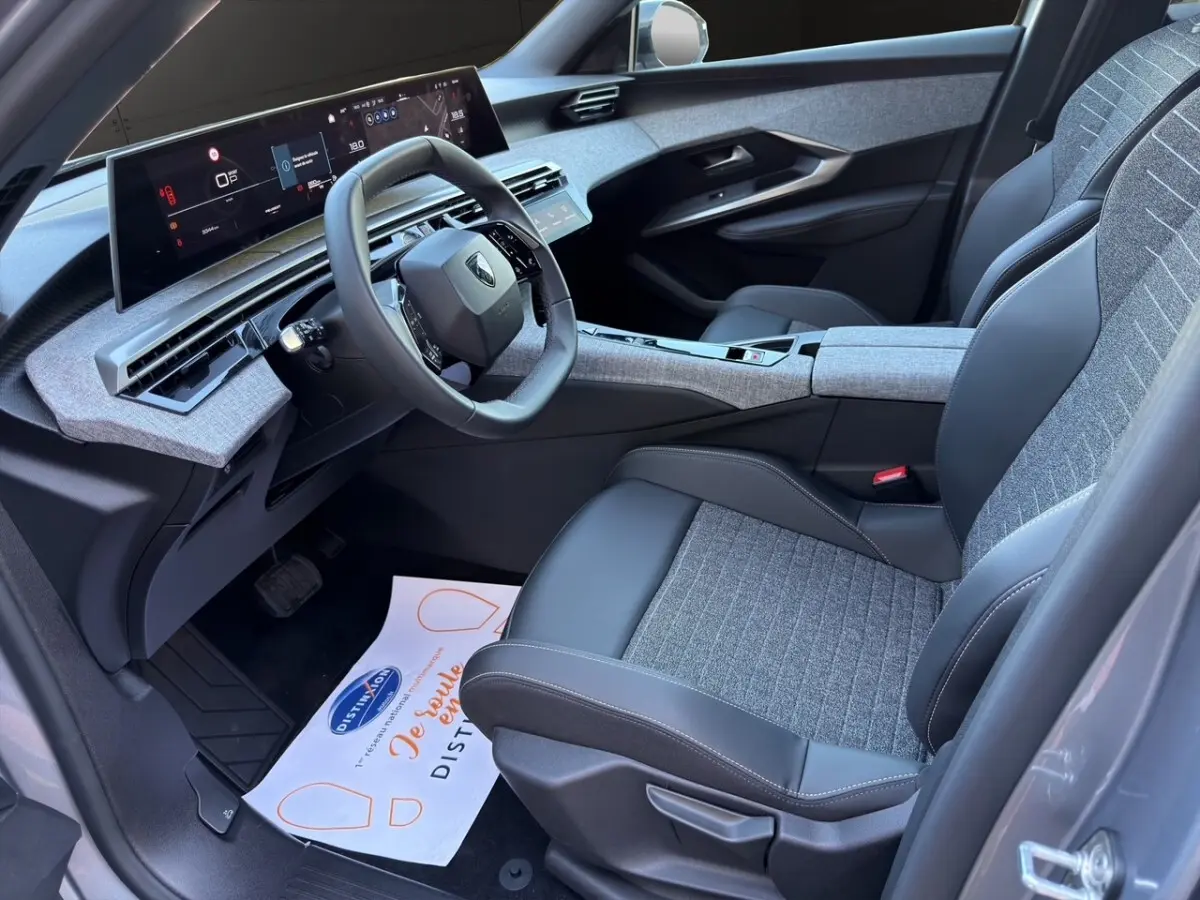 Intérieur avant droit du Peugeot 3008 gris clair 2025, avec tableau de bord numérique et sièges tissu-cuir bicolores.