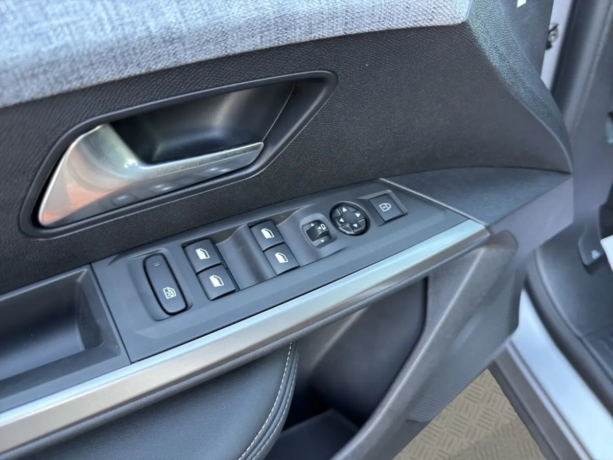 Gros plan sur la porte côté conducteur du Peugeot 3008 gris clair, montrant les commandes des vitres et rétroviseurs.