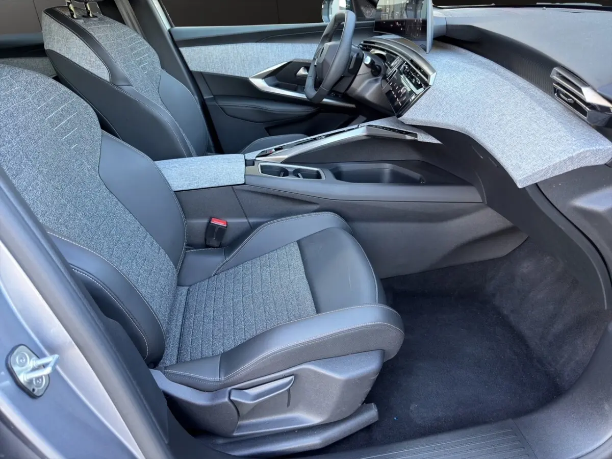 Intérieur avant droit du Peugeot 3008 gris clair 2025, sièges tissu et cuir, tableau de bord avec écran tactile.