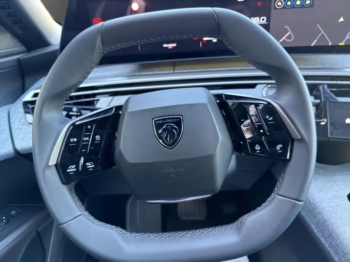 Vue rapprochée du volant cuir noir du Peugeot 3008 2025 avec commandes multifonctions et logo lion central.