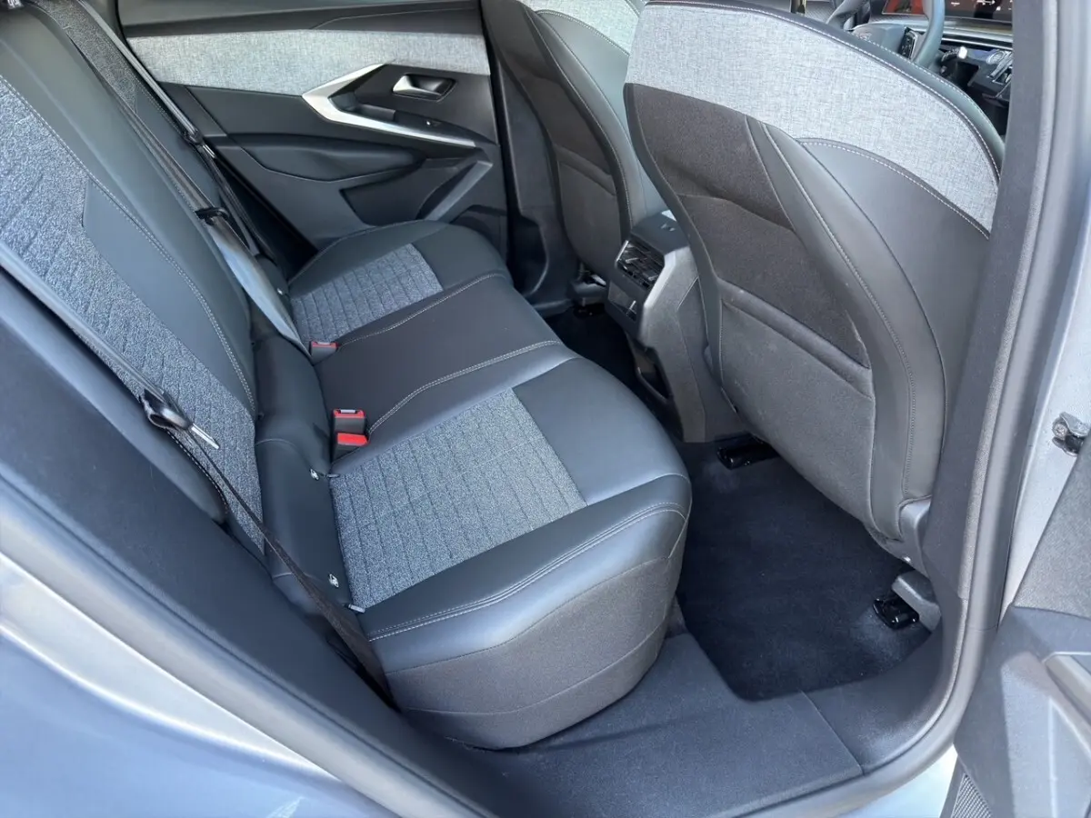 Vue intérieure arrière côté gauche du Peugeot 3008 2025 gris clair, montrant la banquette mixte tissu et cuir.