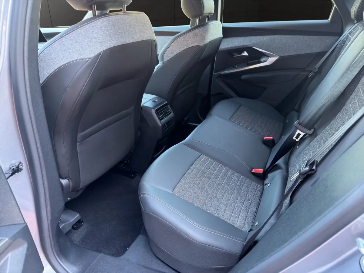 Vue intérieure côté arrière droit du Peugeot 3008 gris clair, montrant la banquette arrière en tissu et cuir avec ceintures de sécurité.