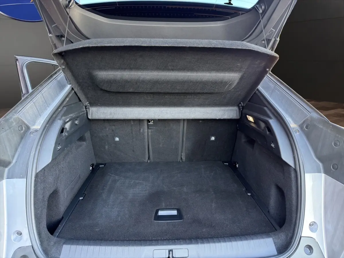 Coffre ouvert vu de l'arrière d'un Peugeot 3008 gris clair, montrant un espace de chargement spacieux et propre.
