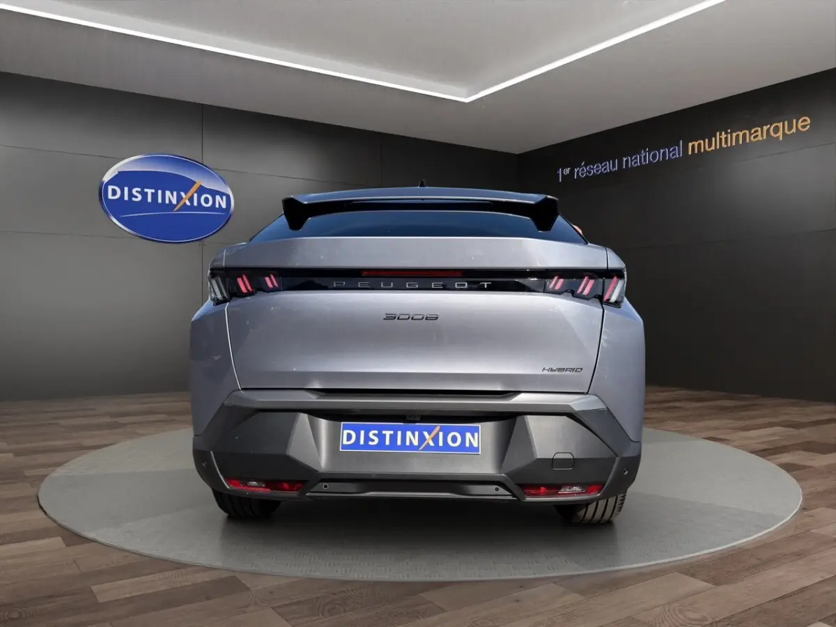Vue arrière d'un Peugeot 3008 hybride gris clair avec feux LED distinctifs et toit panoramique en showroom.