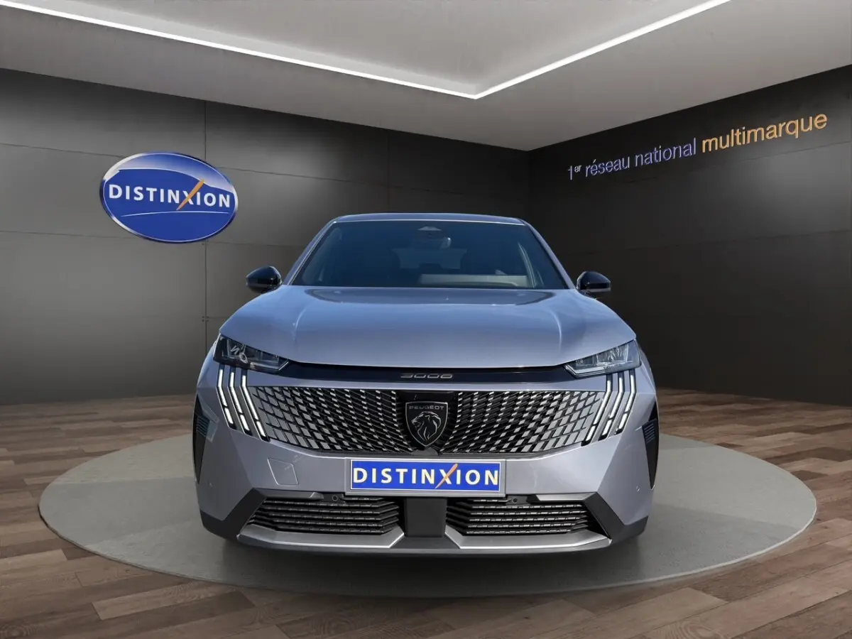 Vue avant du Peugeot 3008 gris clair 2025 avec calandre distinctive et feux LED verticaux en showroom Distinxion.