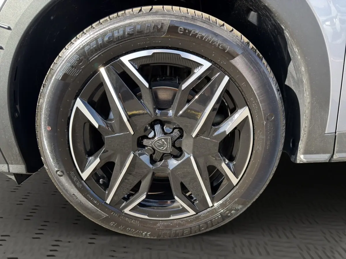 Gros plan sur la roue avant droite du Peugeot 3008 gris clair, jante alliage noire et argentée au design moderne.