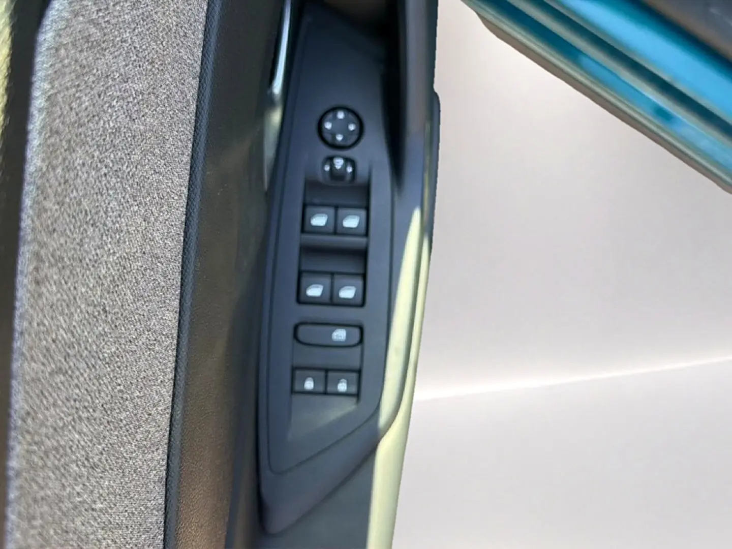 Gros plan sur la commande des vitres électriques côté conducteur de la Peugeot 408 Hybrid 145 allure bleu 2025.