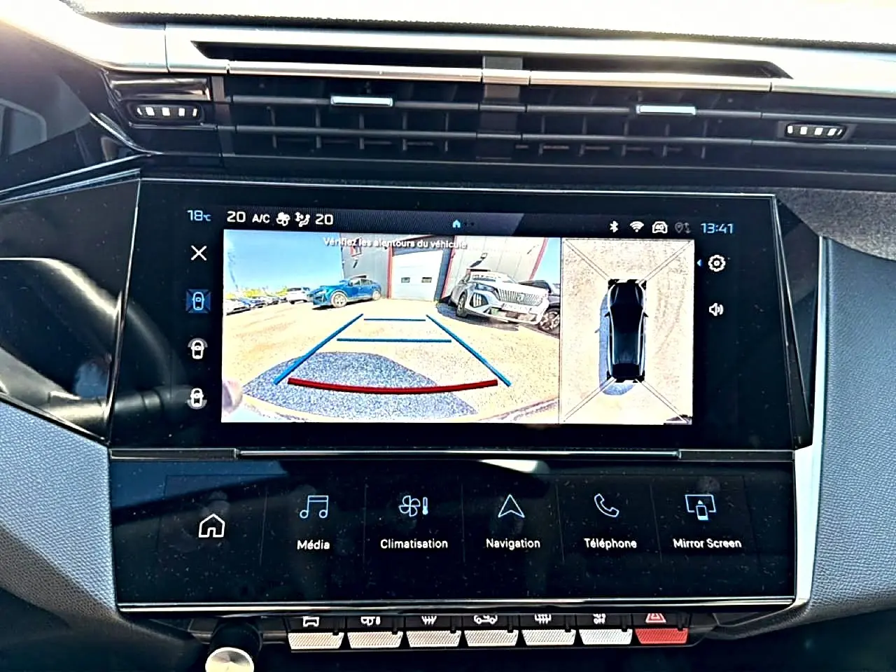 Vue rapprochée de l’écran tactile central du Peugeot 408 Hybrid bleu montrant la caméra de recul et l’aide au stationnement.