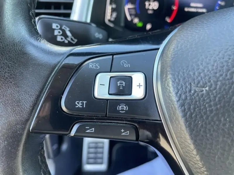 Gros plan sur les commandes de régulateur de vitesse au volant cuir du Volkswagen T-Roc gris foncé 2021.