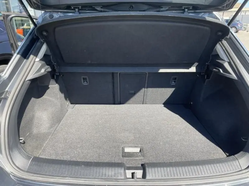 Coffre ouvert vu de l'arrière d'un Volkswagen T-Roc gris foncé métal, montrant un espace de chargement propre et spacieux.