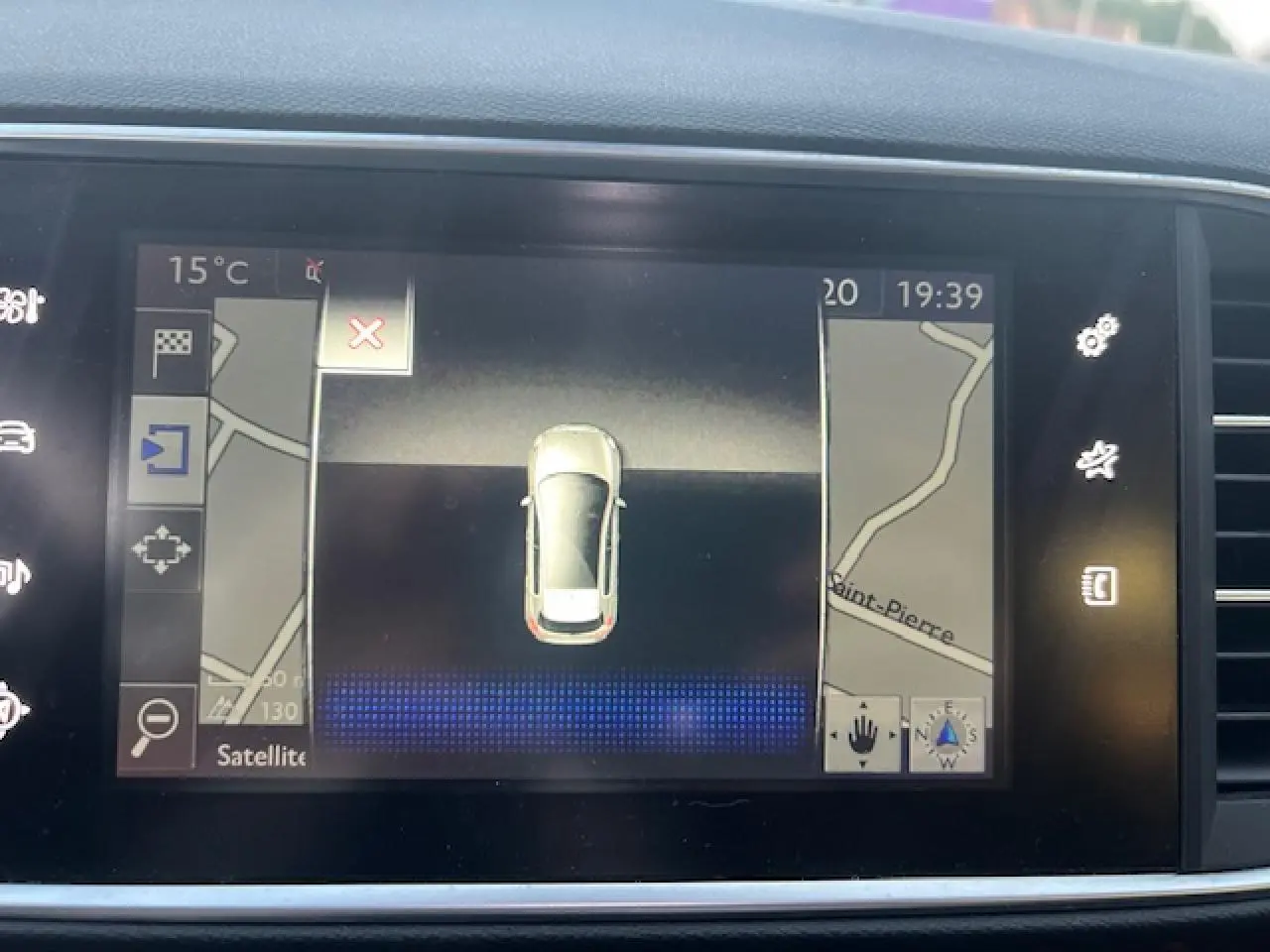 Écran tactile de navigation montrant une vue aérienne de la Peugeot 308 blanche avec carte routière environnante.