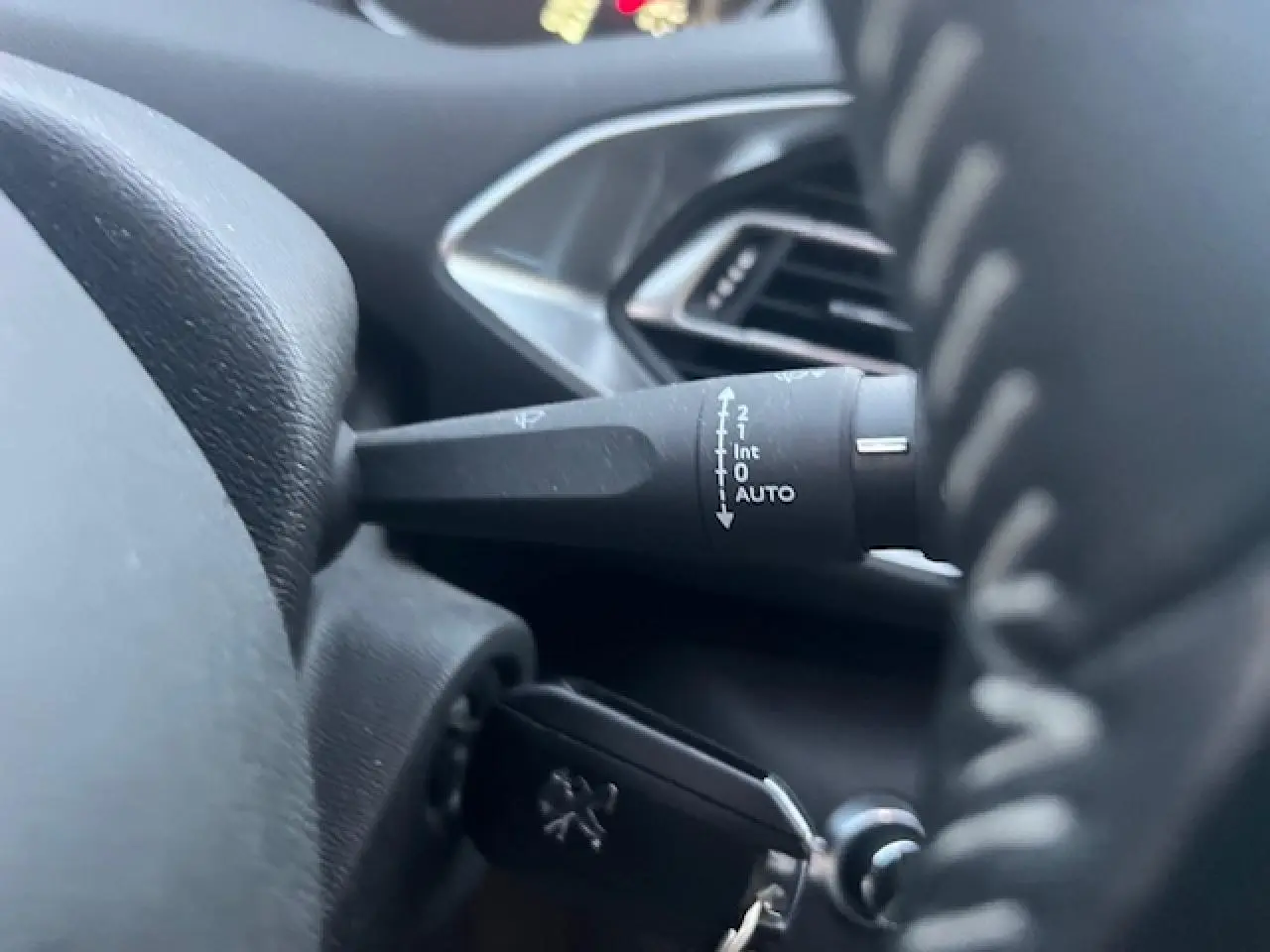 Gros plan sur la manette d’essuie-glace et la clé de contact du tableau de bord intérieur d’une Peugeot 308 blanche.