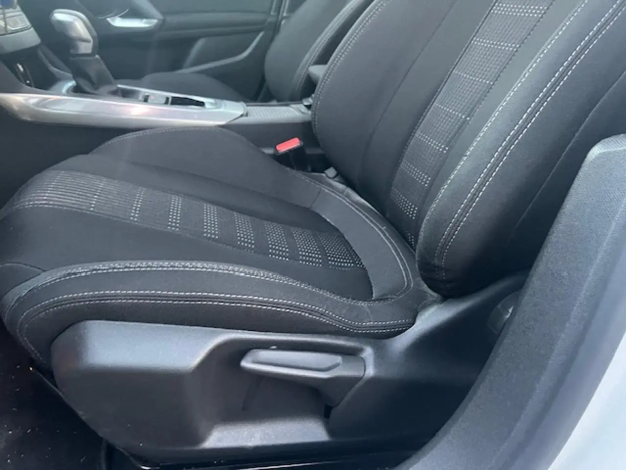 Gros plan sur le siège avant droit noir de la Peugeot 308 blanche, montrant les détails de la sellerie et la commande d'ajustement.