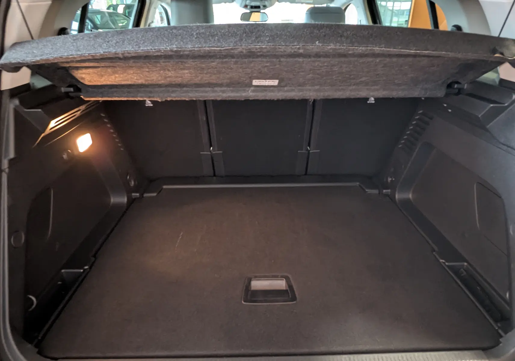 Coffre ouvert du Citroën C5 Aircross hybride gris platinium, vue intérieure arrière montrant l'espace de chargement vide.