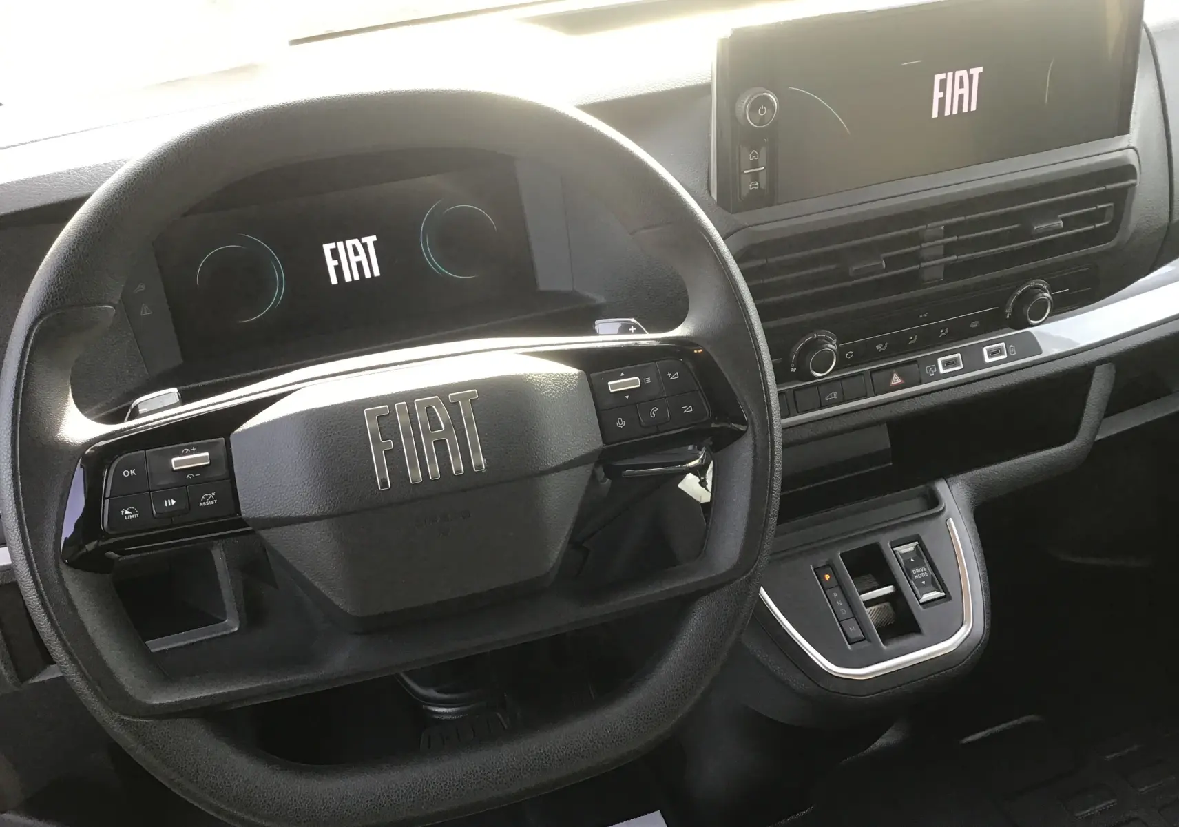 Vue rapprochée de l’intérieur du Fiat Scudo Fourgon 2024, volant noir avec logo FIAT et tableau de bord digital.