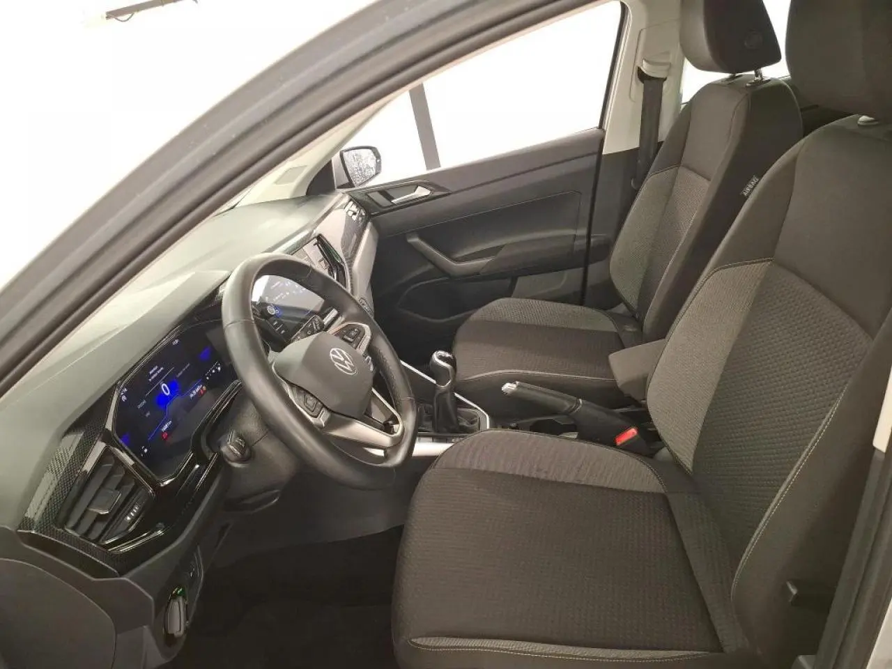 Vue intérieure côté conducteur de la Volkswagen Polo 2023 avec sièges tissu gris et tableau de bord numérique.