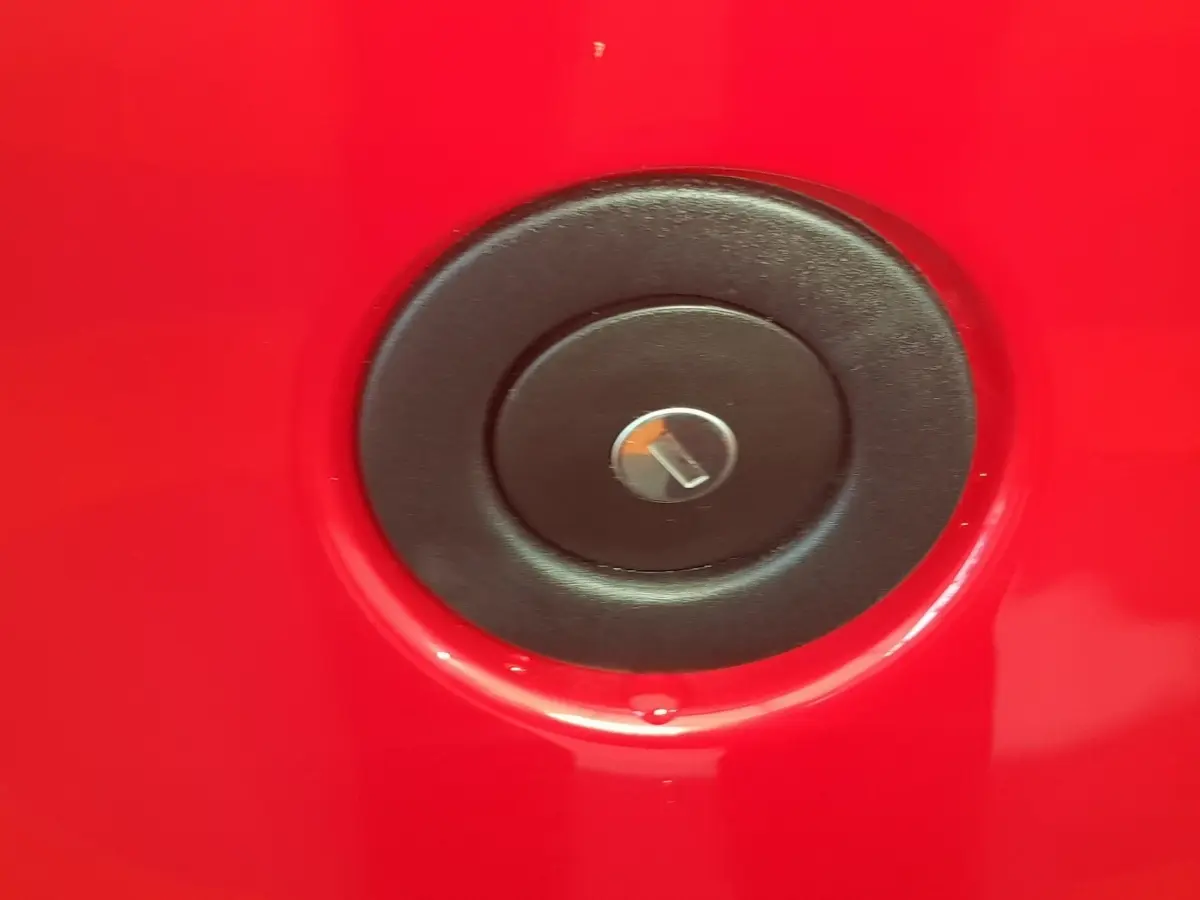 Détail du bouchon de réservoir noir sur la carrosserie rouge vif de l'AIXAM AMBITION 0.5 CITY PACK 2026.