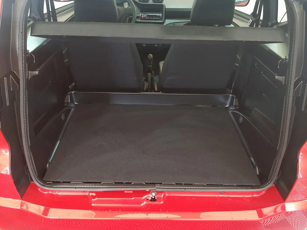 Vue arrière ouverte du coffre d'une Aixam Ambition rouge 2026, montrant l'espace de chargement et les sièges avant.