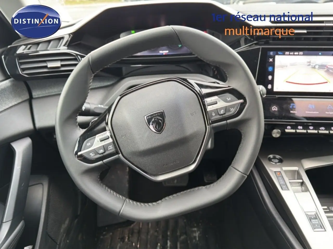 Vue intérieure centrée sur le volant cuir noir et la console centrale high-tech de la Peugeot 308 hybride 2025.