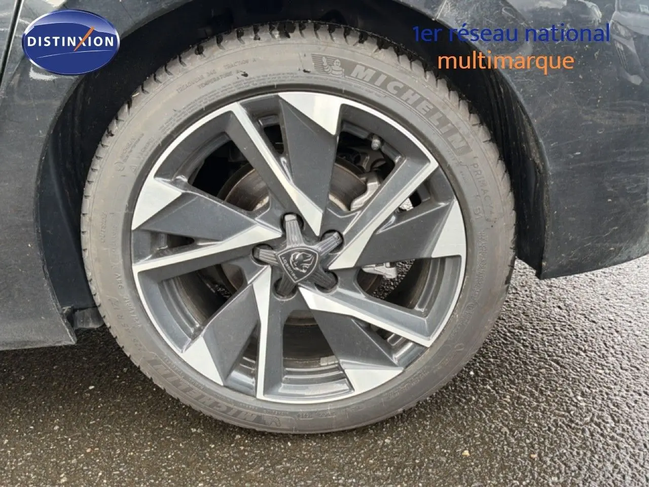 Gros plan sur la roue avant droite noire métal d'une Peugeot 308 1.2 Hybrid 145ch avec jante alliage distinctive.