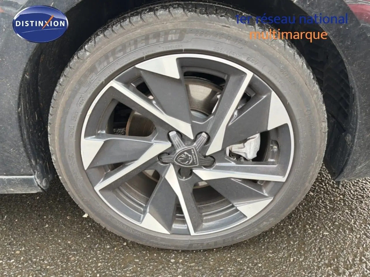 Gros plan sur la jante alliage bicolore de la Peugeot 308 noire, mettant en valeur le logo lion central.