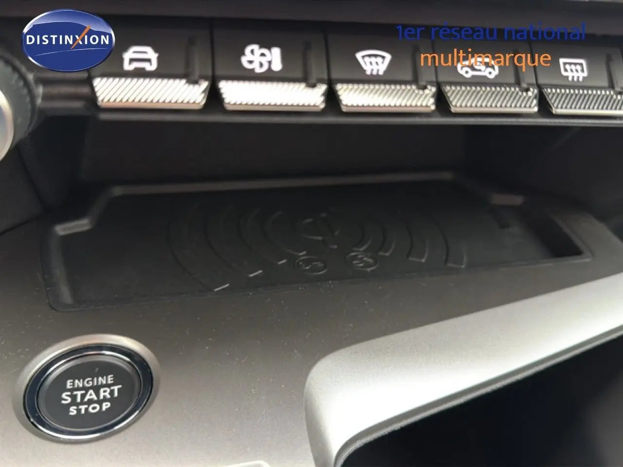 Gros plan sur la console centrale de la Peugeot 308 noire, montrant le bouton start/stop et les commandes de climatisation.