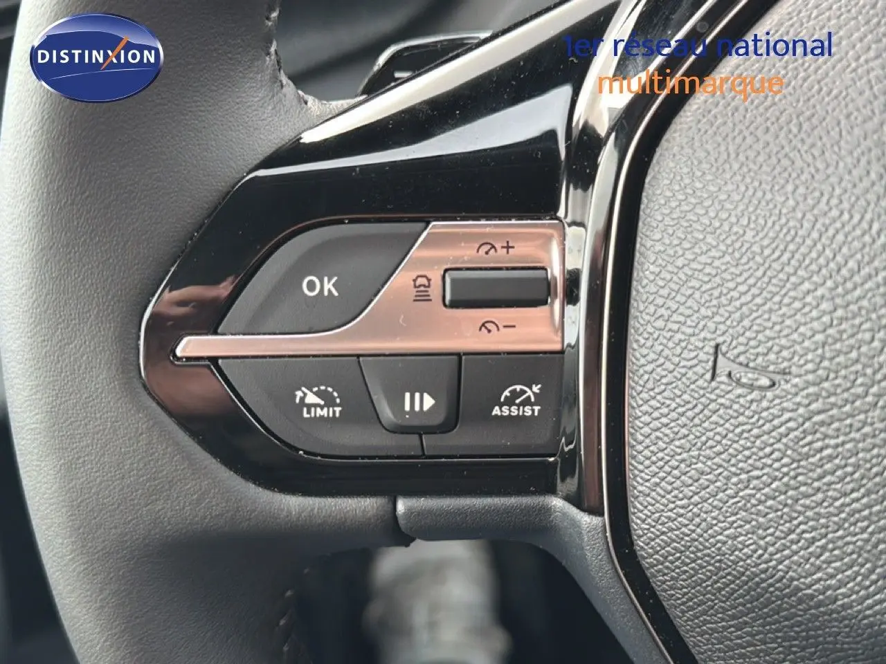 Gros plan sur les commandes au volant noir de la Peugeot 308 1.2 Hybrid 145ch Allure, avec boutons de limitation et assist.