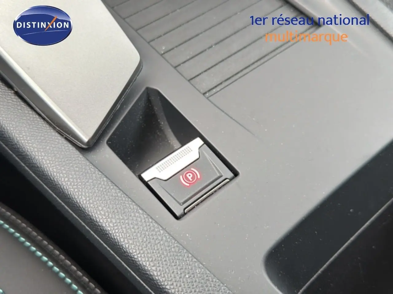 Gros plan sur le bouton de frein à main électronique dans la console centrale d'une Peugeot 308 noire hybride 2025.