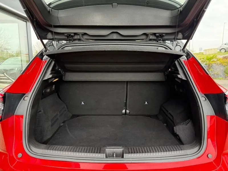 Coffre ouvert vu de l'arrière d'un Renault Austral 2025 rouge flamme, montrant l'espace de chargement vide et la tablette cache-bagages.