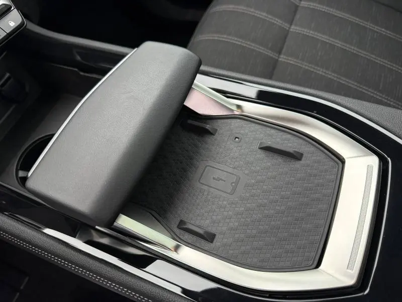 Gros plan sur le chargeur sans fil et l'accoudoir central en cuir noir du Renault Austral 2025, intérieur sobre et moderne.