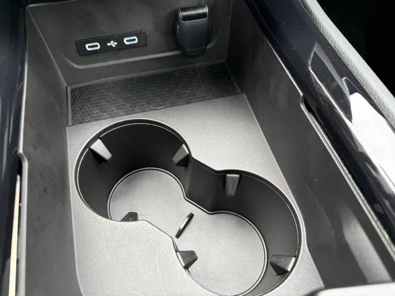 Gros plan sur le porte-gobelets noir et les ports USB dans la console centrale du Renault Austral Rouge Flamme 2025.