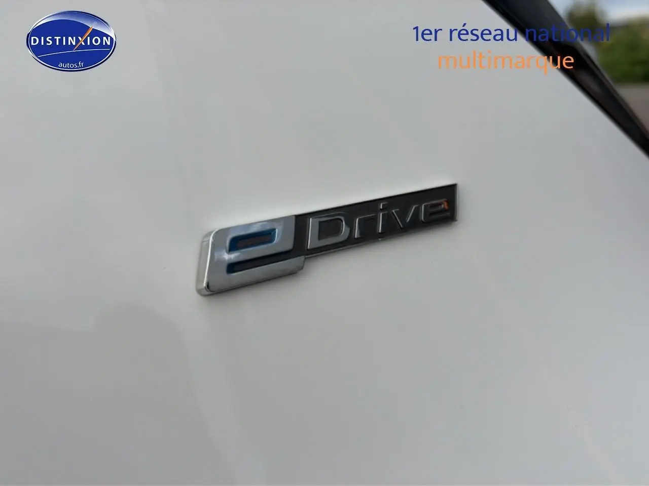Gros plan sur l'emblème eDrive argent et bleu sur la carrosserie gris argent d'une BMW Série 2 Active Tourer.