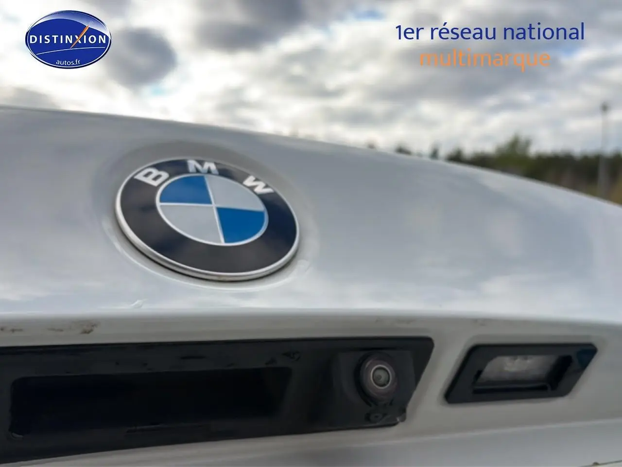 Gros plan sur le logo BMW gris argent avec caméra de recul et poignée de coffre sur une Série 2 Active Tourer.