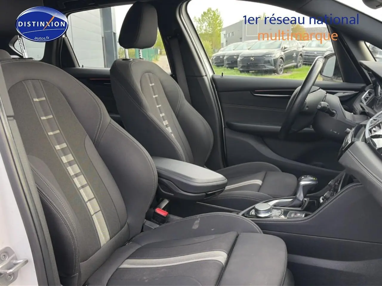 Vue intérieure côté conducteur de la BMW Série 2 Active Tourer 225xea, sièges tissu anthracite avec accoudoir central.
