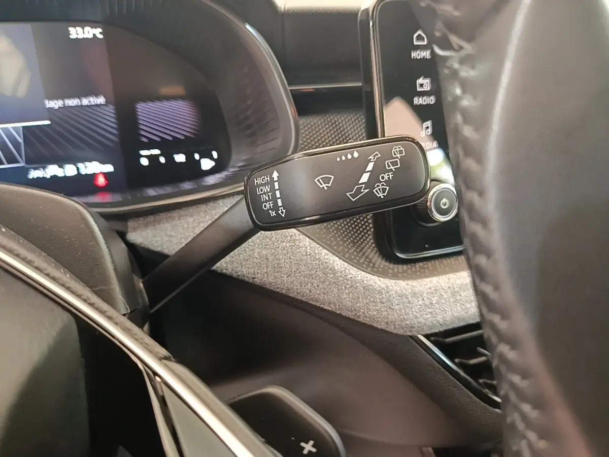 Gros plan sur la commande d’essuie-glace à gauche du volant cuir alu du Skoda Scala 1.5 TSI 2024, tableau de bord numérique visible.