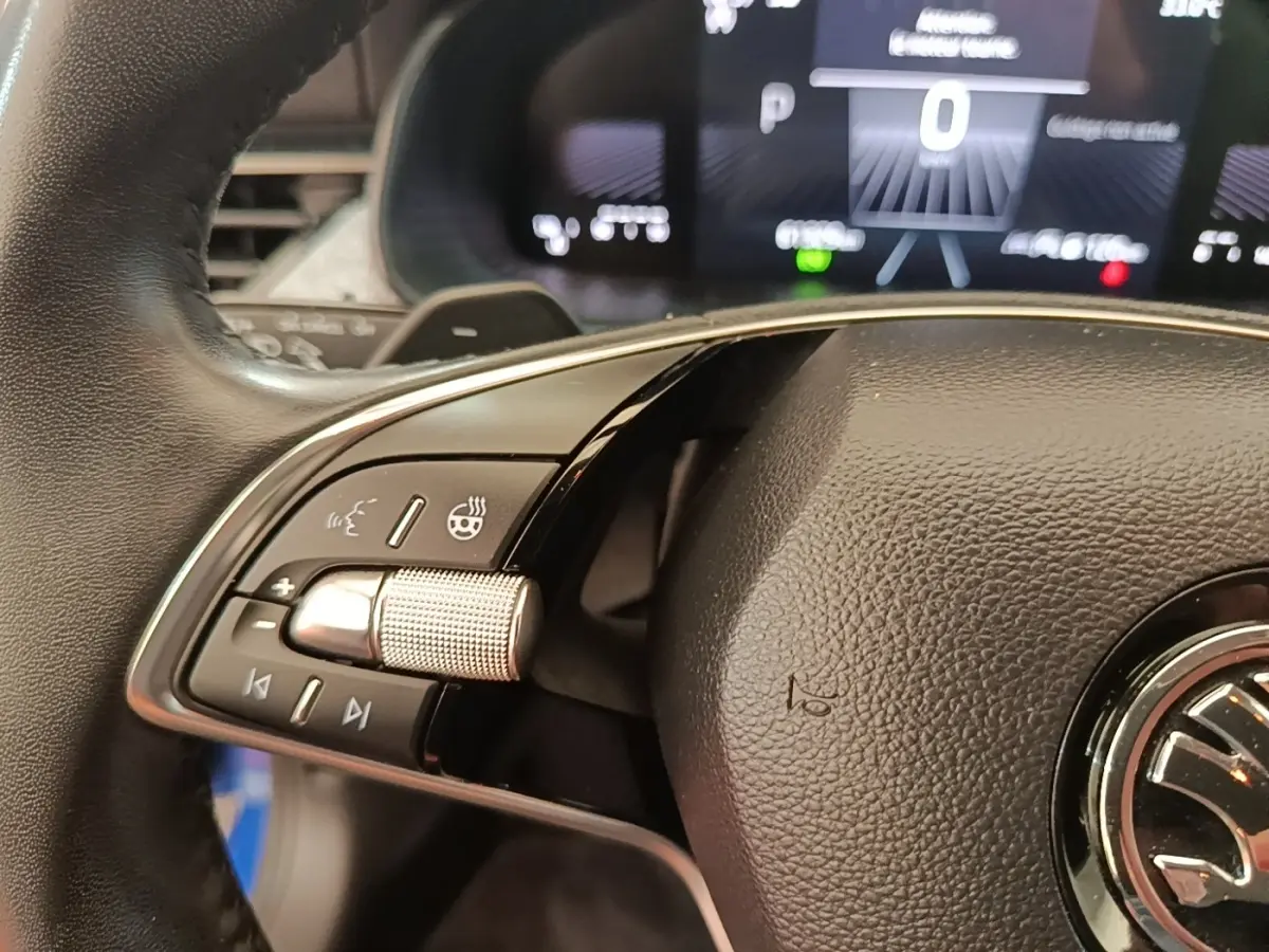 Gros plan sur le volant cuir et alu multifonctions côté gauche du Skoda Scala 2024, avec tableau de bord numérique en arrière-plan.