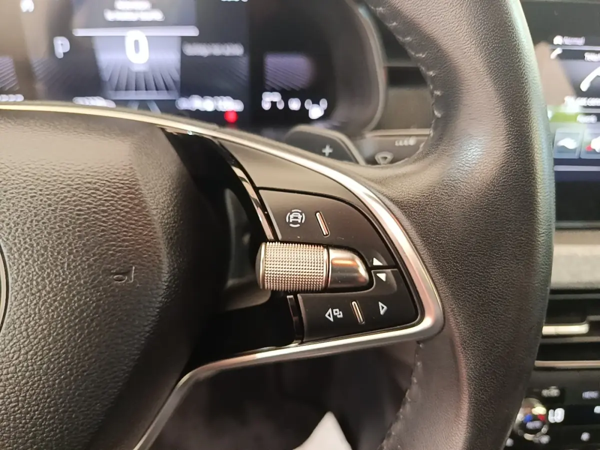 Gros plan sur le volant cuir et alu de la Skoda Scala 2024 avec commandes multifonctions et tableau de bord numérique flou.