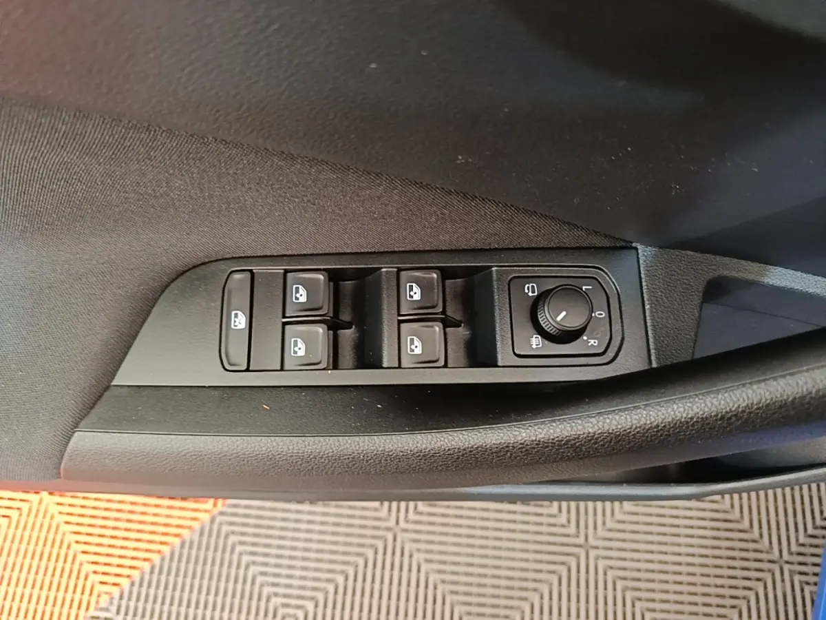 Gros plan sur les commandes des vitres et rétroviseurs côté conducteur d'une Skoda Scala 2024 bleu.