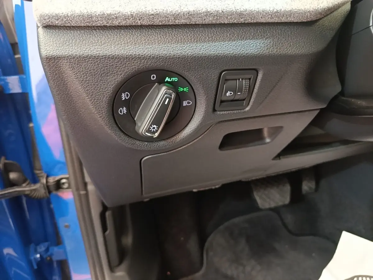 Détail du tableau de bord côté gauche d’une Skoda Scala bleu 2024 avec commande des phares et réglage hauteur.