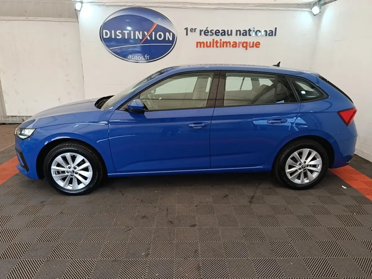 Vue latérale droite d'une Skoda Scala bleu 2024 stationnée en intérieur avec jantes alliage argentées.