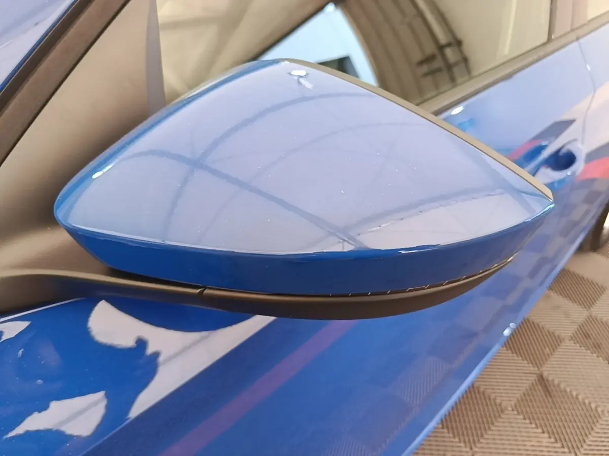 Rétroviseur côté gauche bleu de la Skoda Scala 1.5 TSI 2024 avec carrosserie bleue visible en arrière-plan.