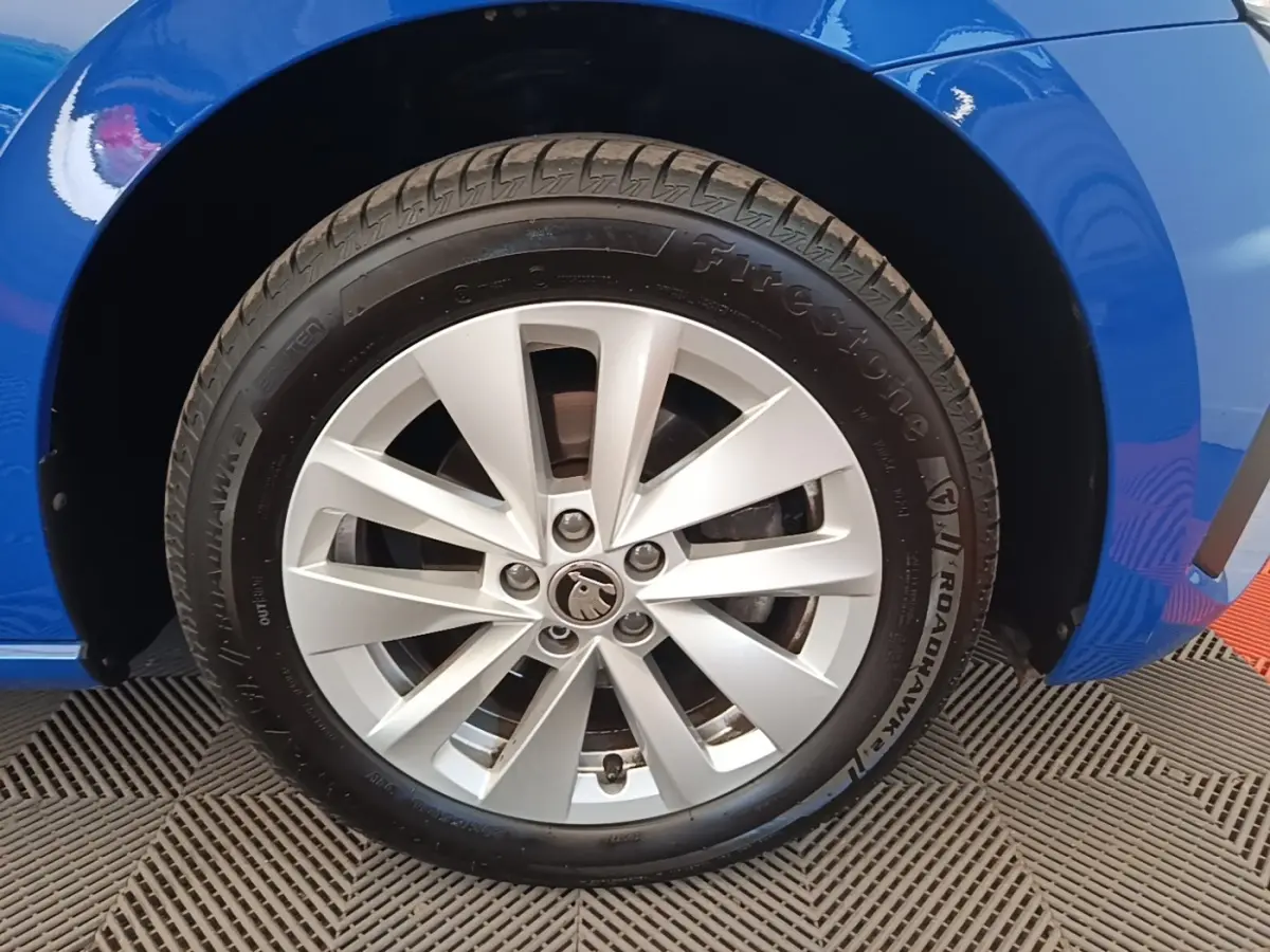 Gros plan sur la roue avant gauche d’une Skoda Scala bleu, avec jante alliage argentée et pneu Firestone.