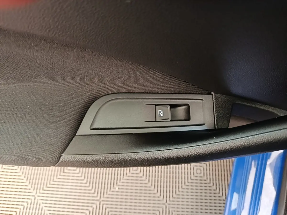 Détail de la commande de verrouillage centralisé sur la porte côté gauche d’une Skoda Scala bleue 2024.